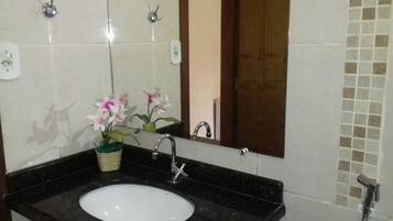 Un baño con lavamanos blanco, encimera negra y un espejo.
