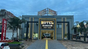 Un hotel con una entrada destacada, un número de contacto y una zona de estacionamiento.