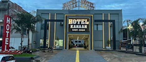 A hotel with a prominent entrance, a contact number, and a parking area.