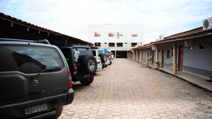 Un sendero pavimentado bordeado de vehículos estacionados que conduce a un edificio con varias ventanas y techo de tejas.