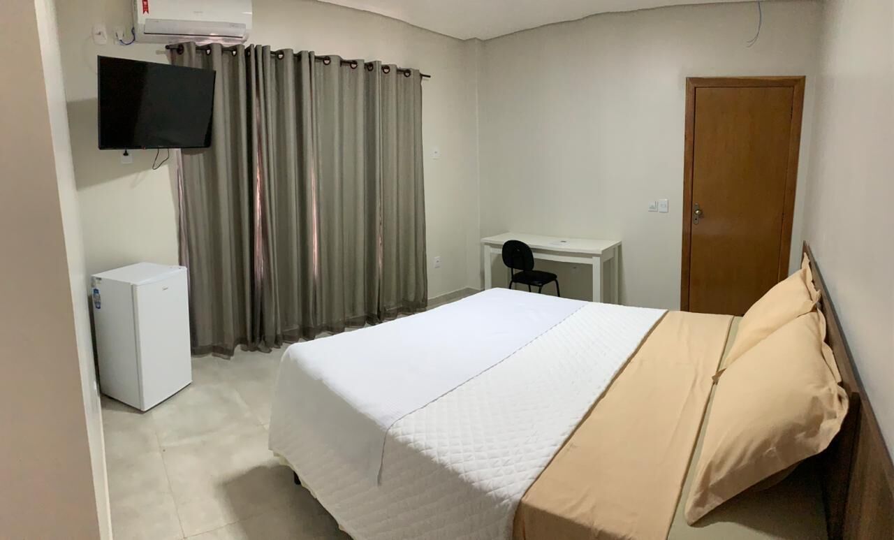Een hotelkamer met een bed, een bureau, een stoel, een televisie en een kledingkast.