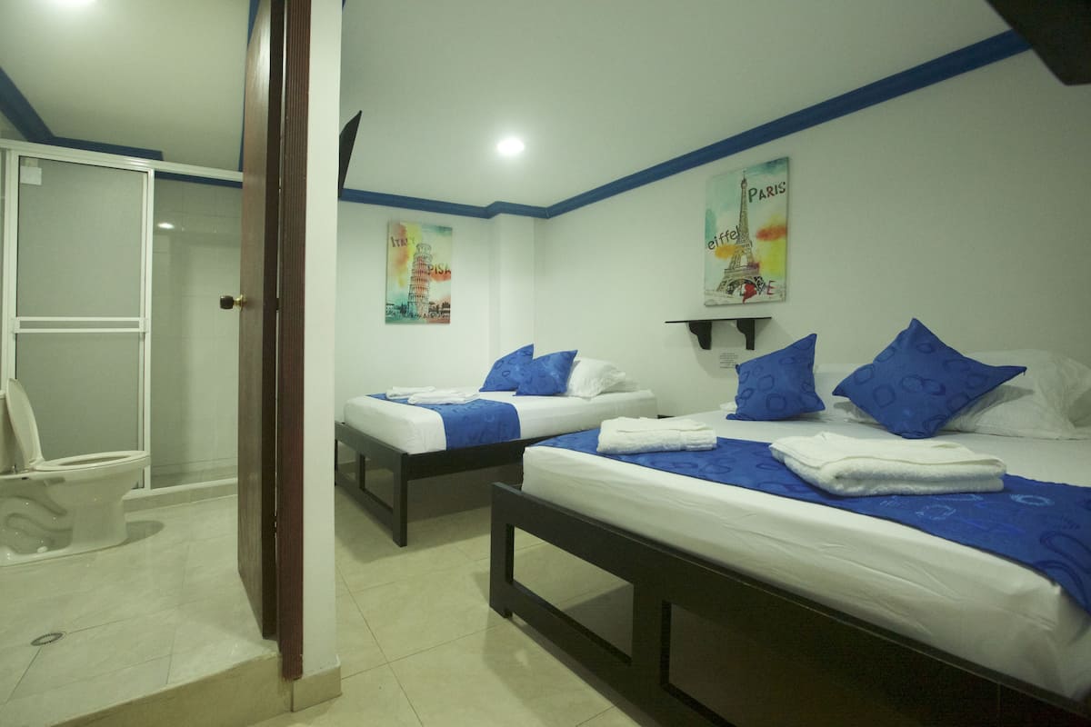 A hotel room with two beds, a shower, and a toilet.