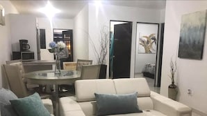 Departamento Deluxe, vista a la bahía | Área de sala de estar | Televisión de pantalla plana 