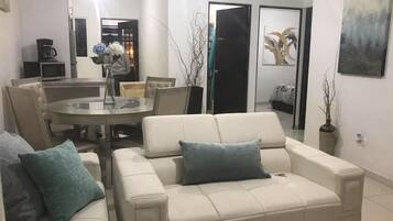 Departamento Deluxe, vista a la bahía | Área de sala de estar | Televisión de pantalla plana