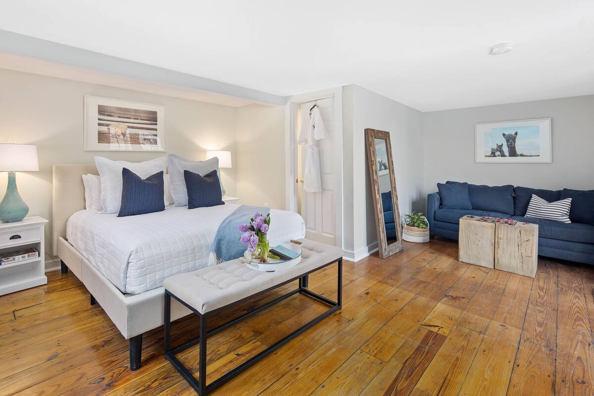 A modern bedroom with a bed, bedside table, nightstand, and a blue sofa.