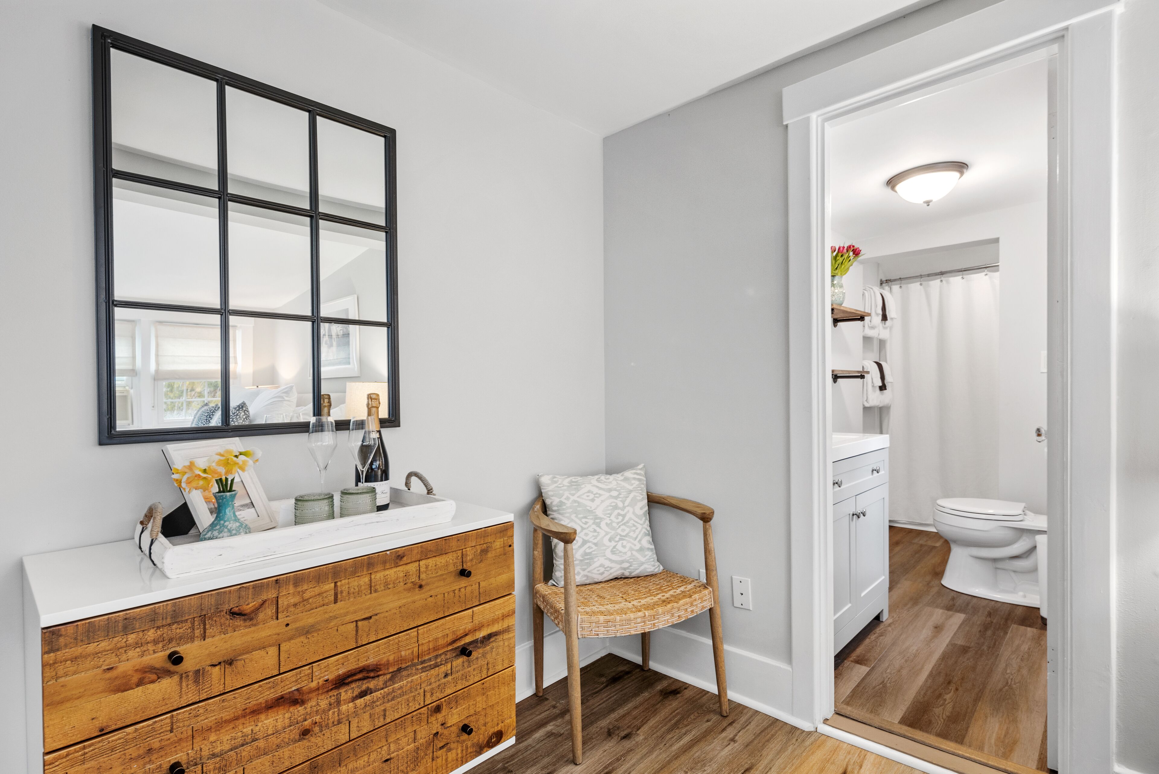 Un baño con tocador de madera, un espejo, una silla y zona de ducha.