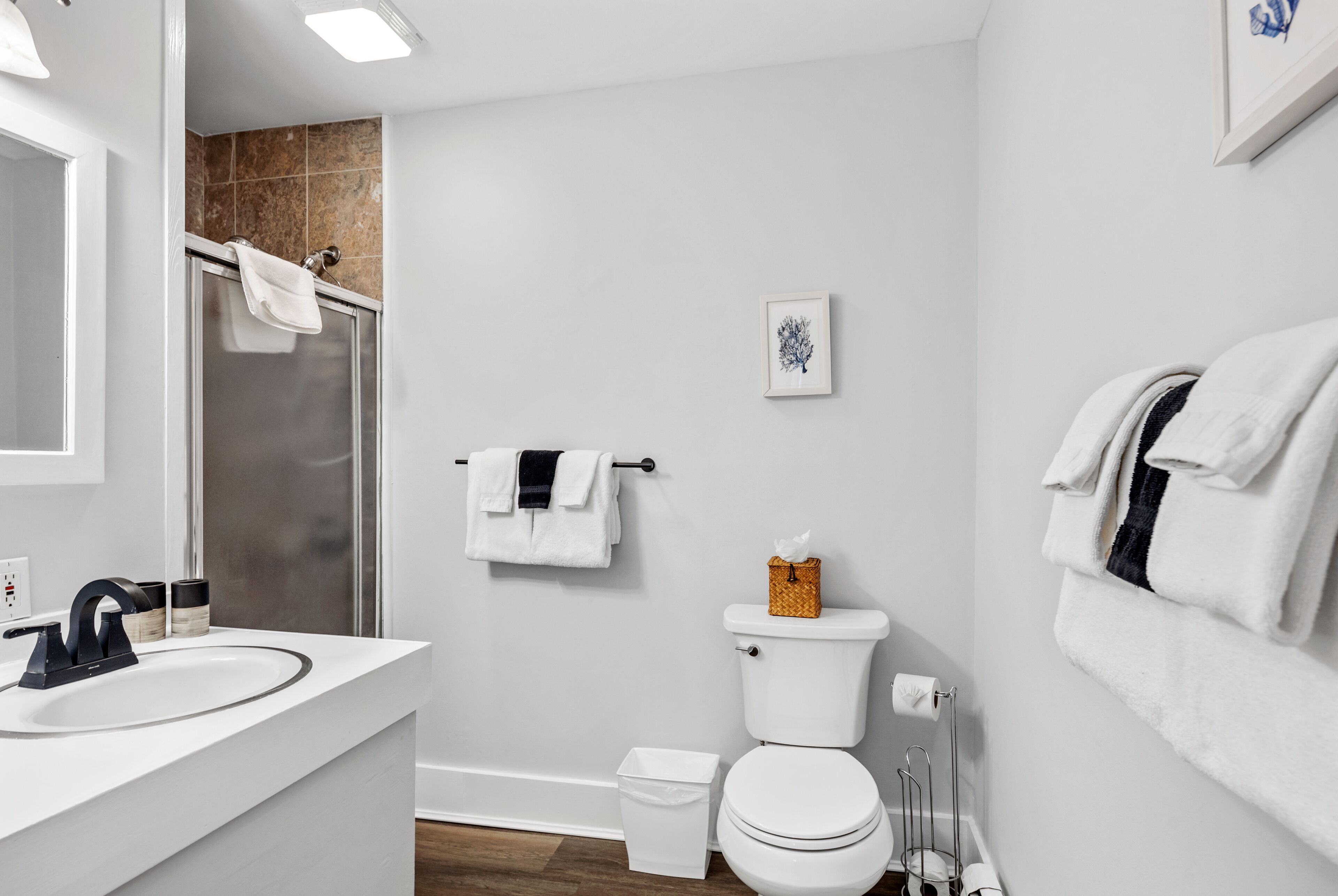 Un baño moderno con un lavabo blanco, cabina de ducha de vidrio, inodoro y perchero para toallas.