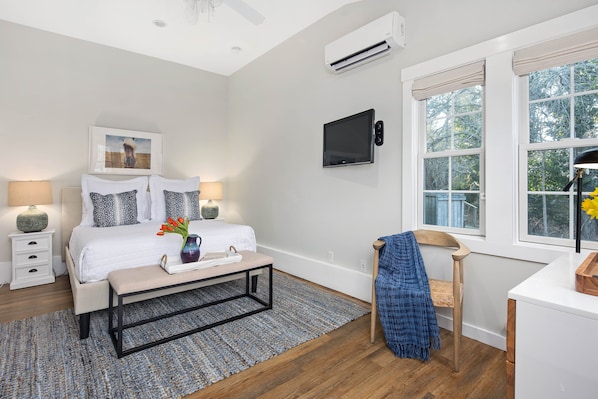 A bedroom with a bed, bedside tables, a TV, a window with a view, and a ceiling fan. - Lamberts Cove Inn (Vineyard Haven)