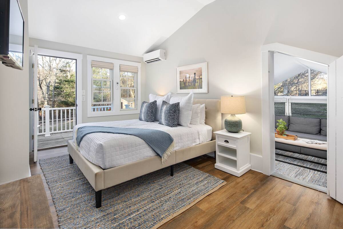 A bedroom with a bed, bedside tables, a window, and a view of the outdoors.