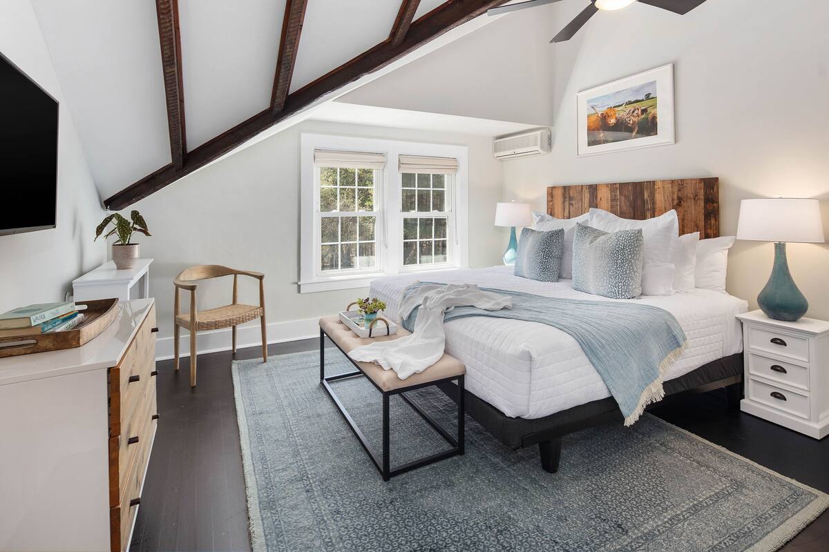 A bedroom with a bed, bedside tables, a chair, a window, and a ceiling fan.