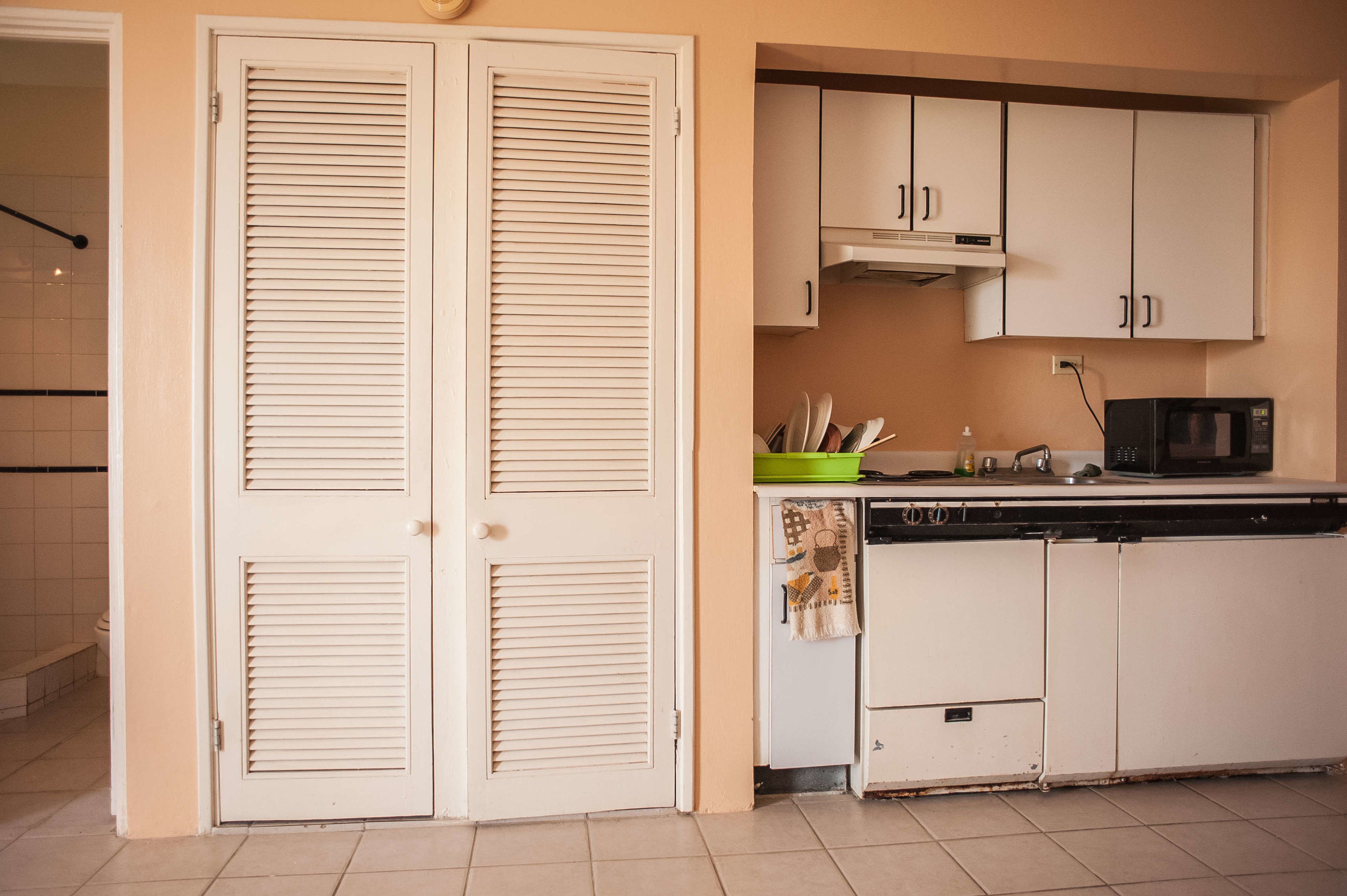 A compact kitchen with white cabinets, a microwave, and a small countertop.