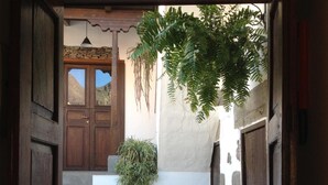 A narrow stone pathway leading to a wooden door with a stone wall and a hanging plant above.