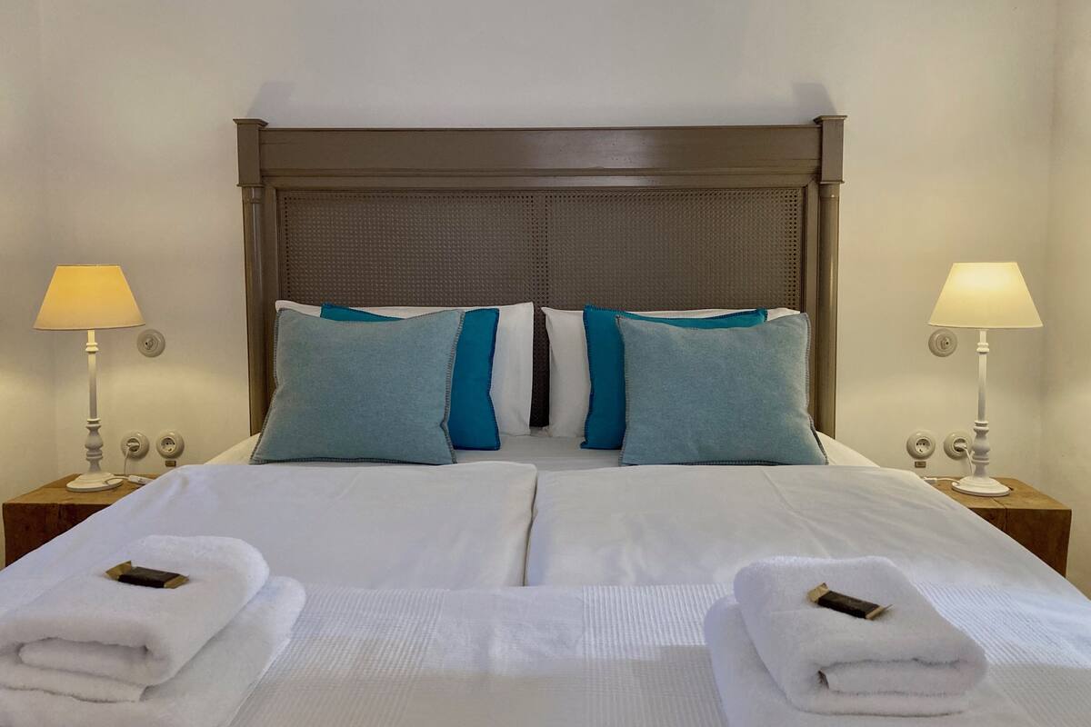 A hotel room with a large bed, two nightstands, two lamps, and two towels.