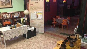 A cozy bookstore with a table displaying books and a poster on the wall. - Kinmen RuJia B&B (Jincheng)