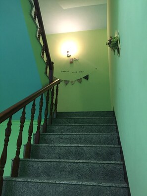 A staircase with a wooden handrail and a light fixture on the wall.