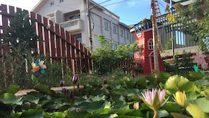 A garden with water lilies and a red building with a white balcony. - Kinmen RuJia B&B (Jincheng)