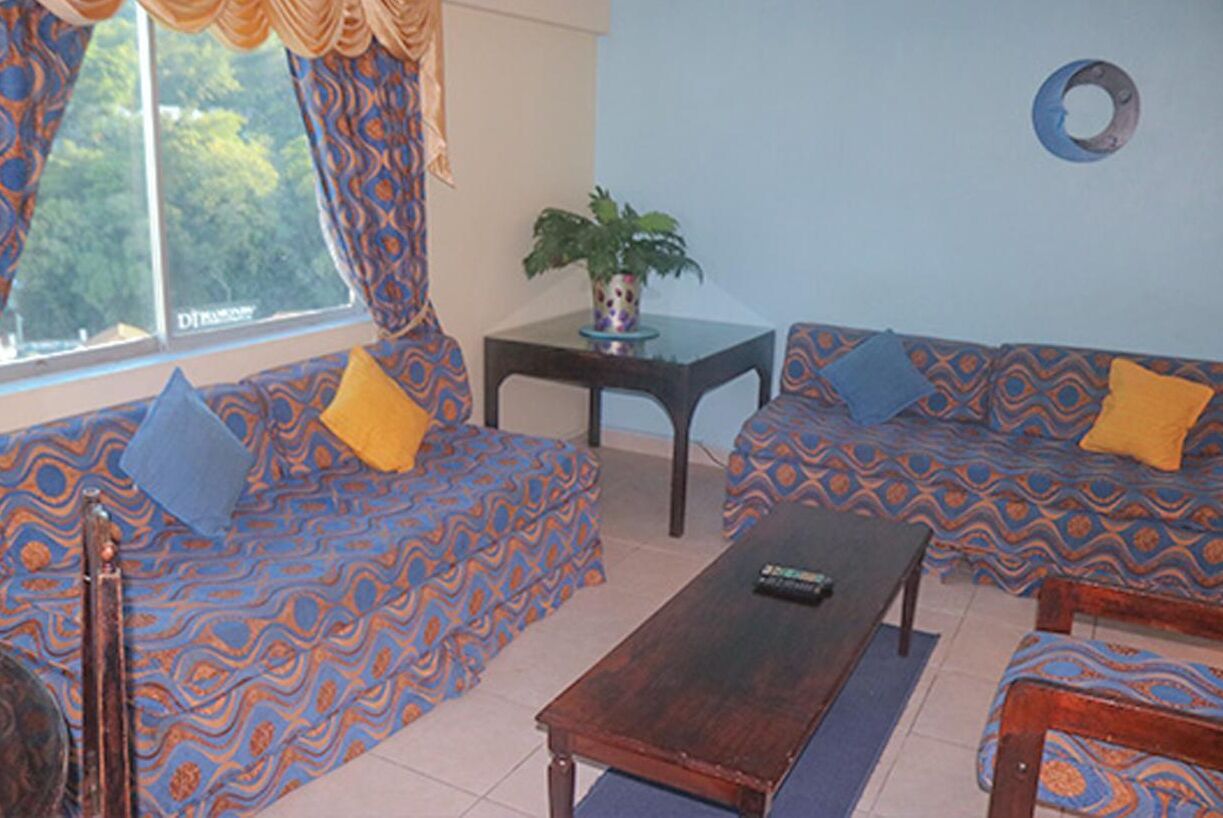 A living room with patterned sofas, a wooden coffee table, and a potted plant on a small table.