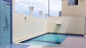 Une petite piscine extérieure avec des murs et un sol carrelés.