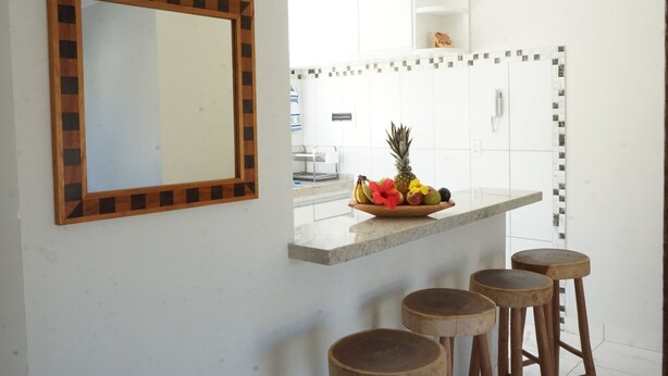 Une cuisine moderne dotée d’un îlot central, de tabourets en bois et d’un miroir avec un cadre géométrique.
