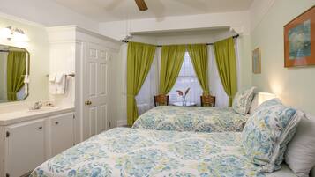 A bedroom with a large bed, a vanity with a mirror, and a window with green curtains.