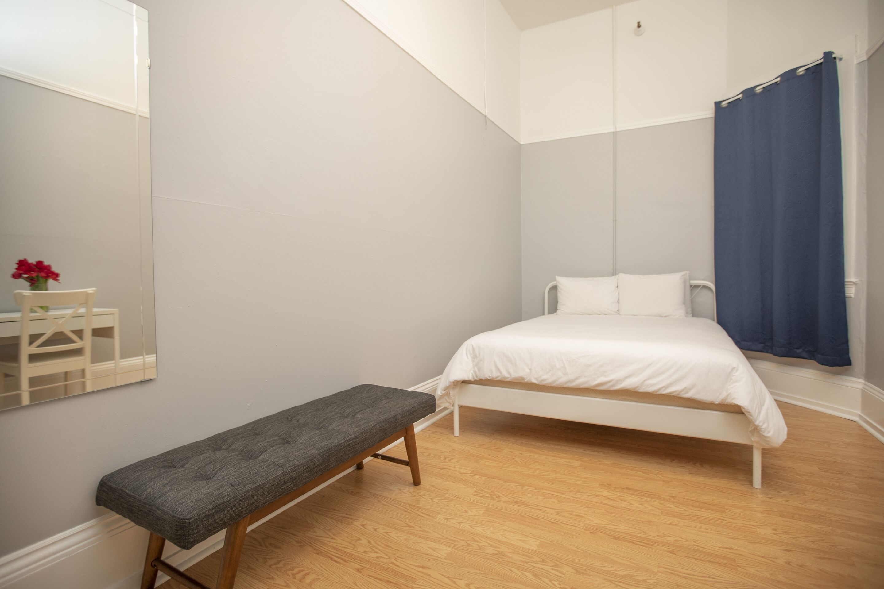 Ein Schlafzimmer mit Bett, Bank und Spiegel.