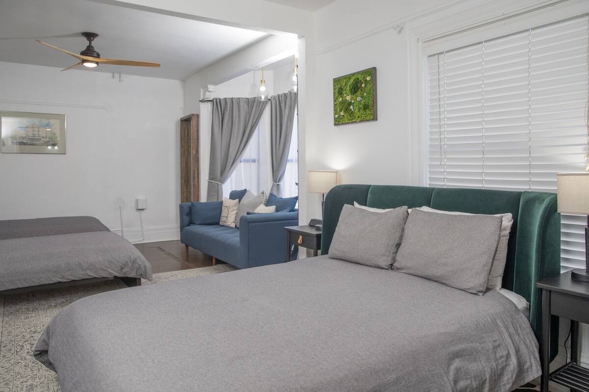 A bedroom with a large bed, a blue sofa, and a green headboard.