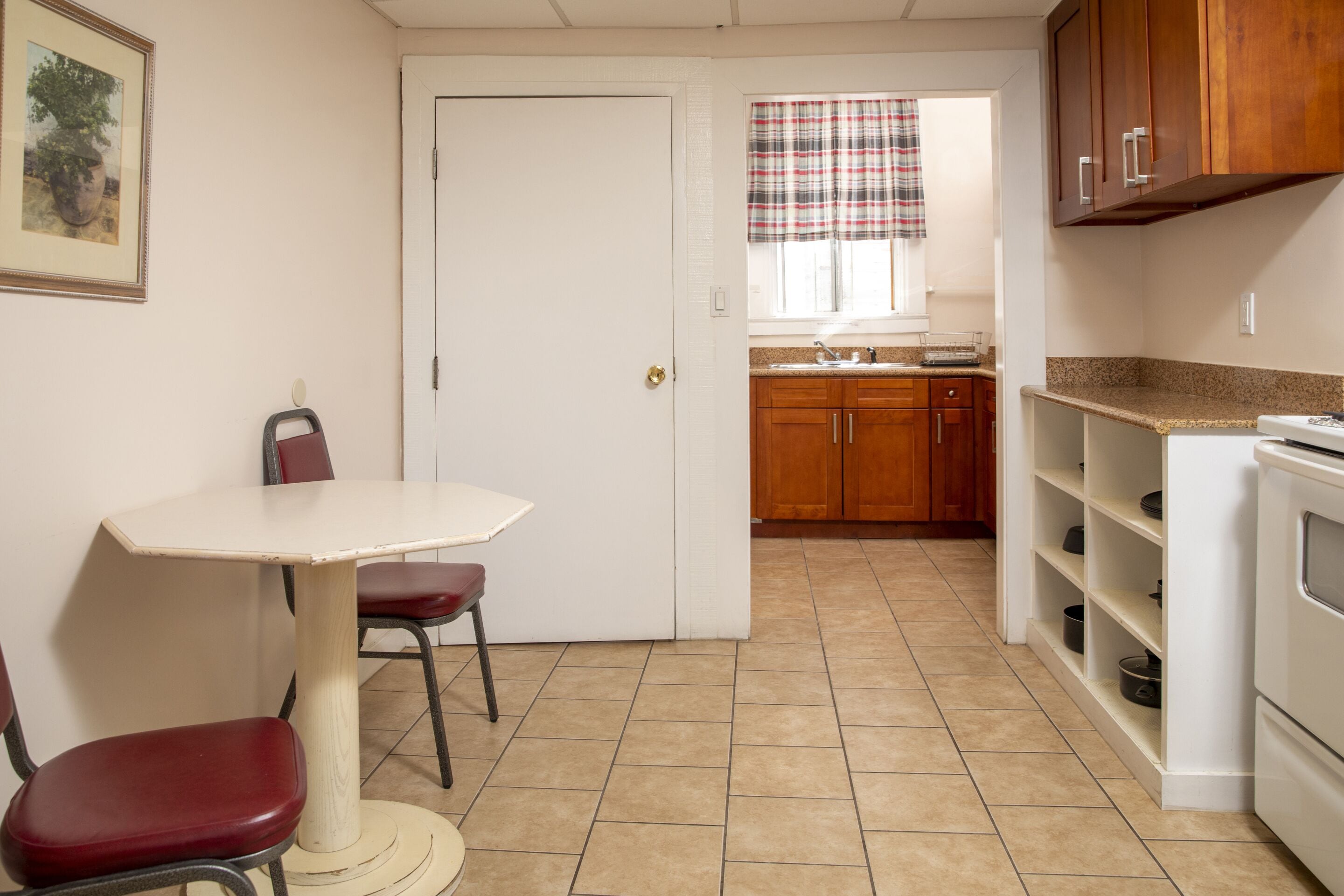 A compact kitchen with a dining table, chairs, wooden cabinets, and a built-in oven.