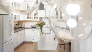 A modern kitchen with white cabinetry, a central island, and a dining area with a wooden table. - Hayes Valley Inn (San Francisco)