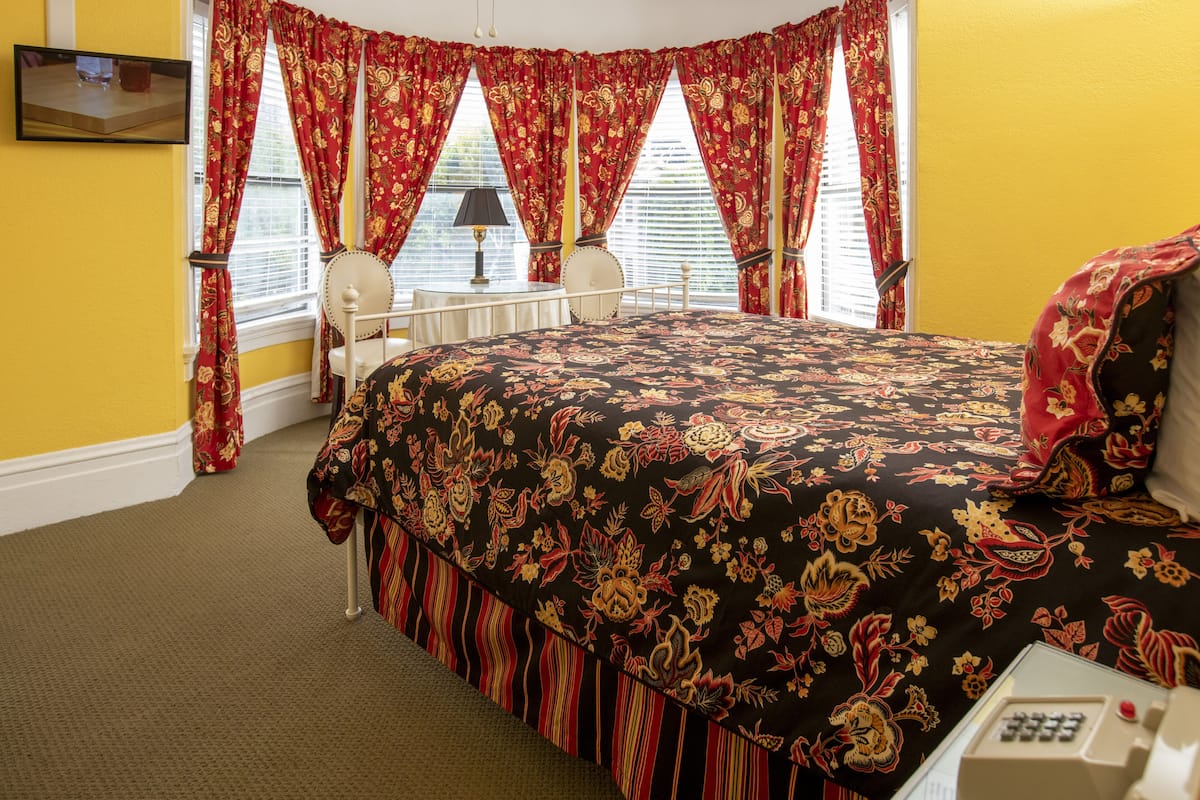 A bedroom with a large bed, a bedside table, a lamp, and a chair.