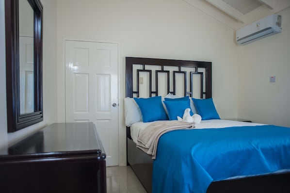 A neatly arranged bedroom with a bed, a dresser, and a door.
