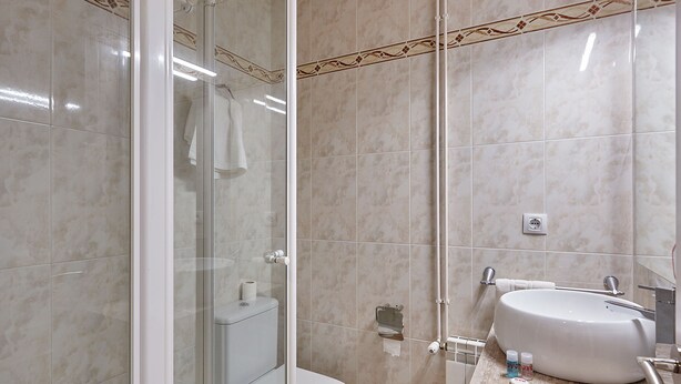 A modern bathroom with a glass-enclosed shower, a toilet, and a sink with a mirror. - Hostal Nobadis (Cervera)