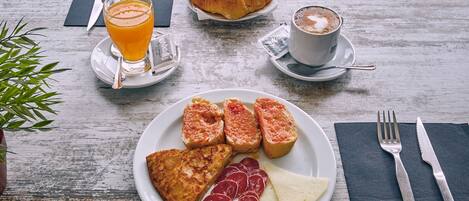 A breakfast setting with croissants, coffee, orange juice, and a plate of toast, ham, and cheese on a wooden table.