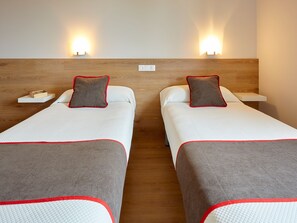 A hotel room with two single beds, each with a pillow and a bedside table. - Hostal Nobadis (Cervera)