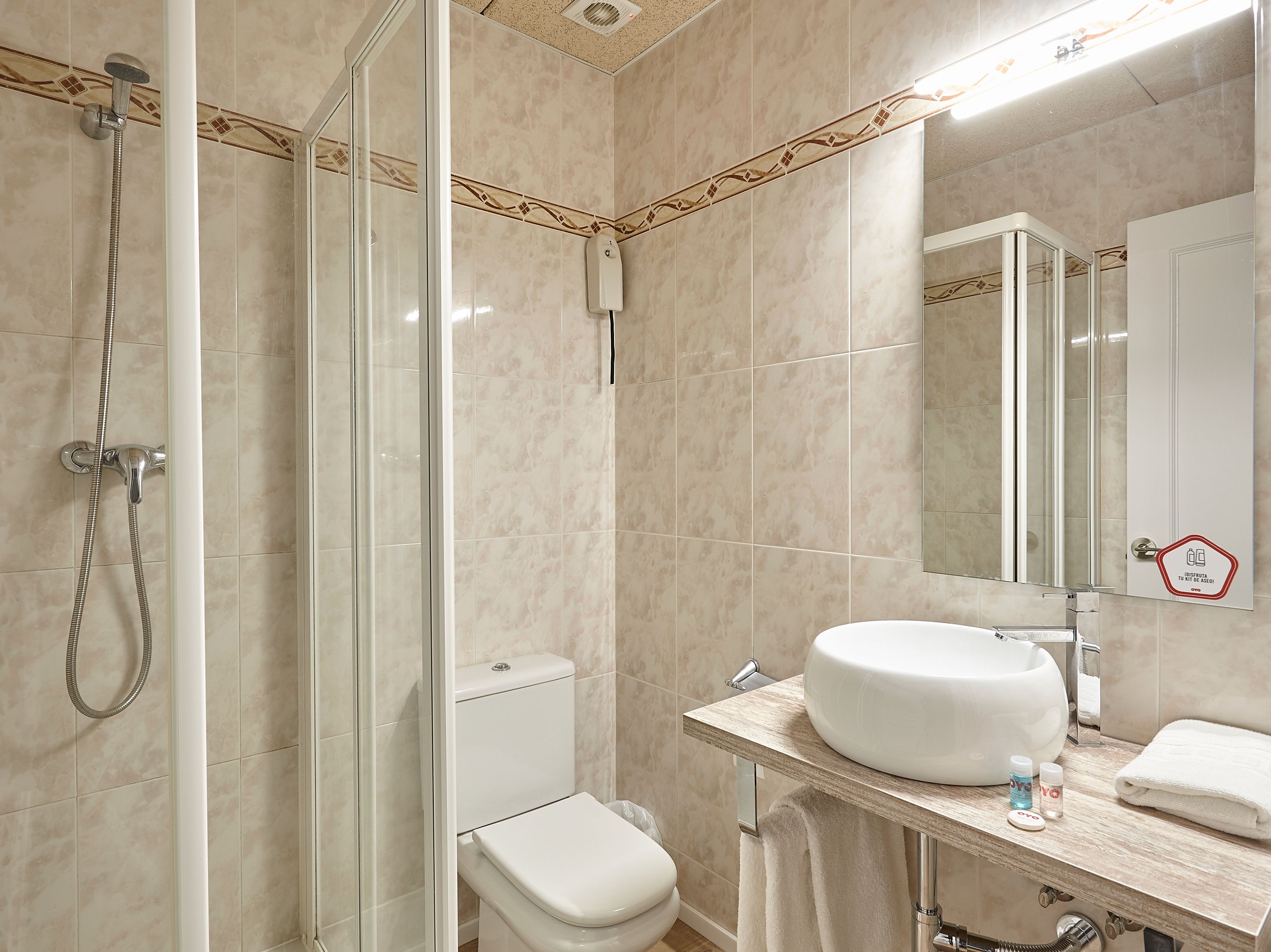 A bathroom with a glass-enclosed shower, a toilet, and a sink with a mirror above it.