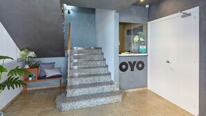 A modern interior with a granite staircase, a reception desk with the name 'OYO', and a door to the right. - Hostal Nobadis (Cervera)