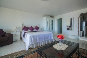 A bedroom with a bed, nightstands, a dresser, a glass coffee table, and a mirror. - Tall Palms (Montego Bay)