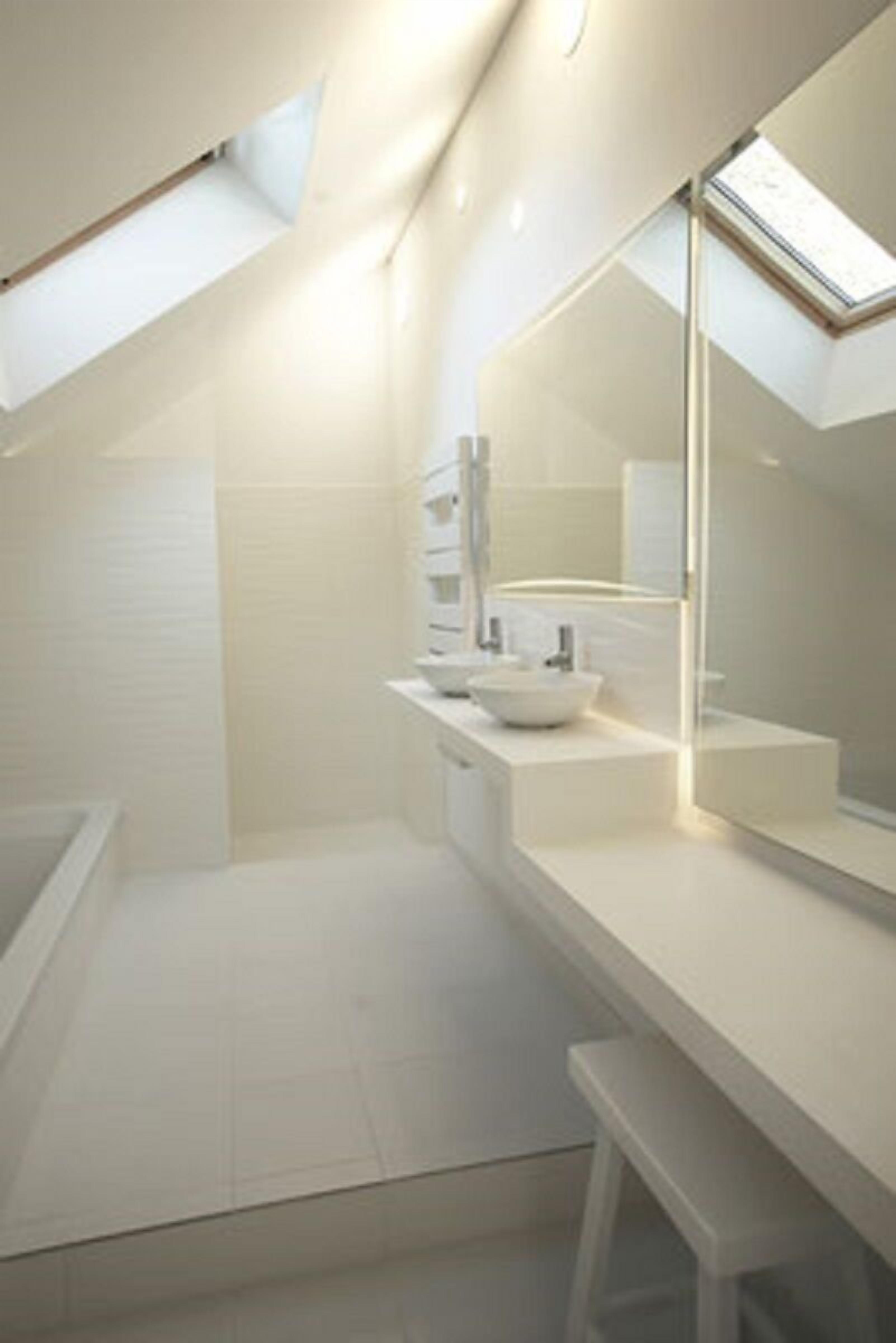 Un bagno moderno con una finestra sul tetto, un ampio specchio e un lavandino bianco.