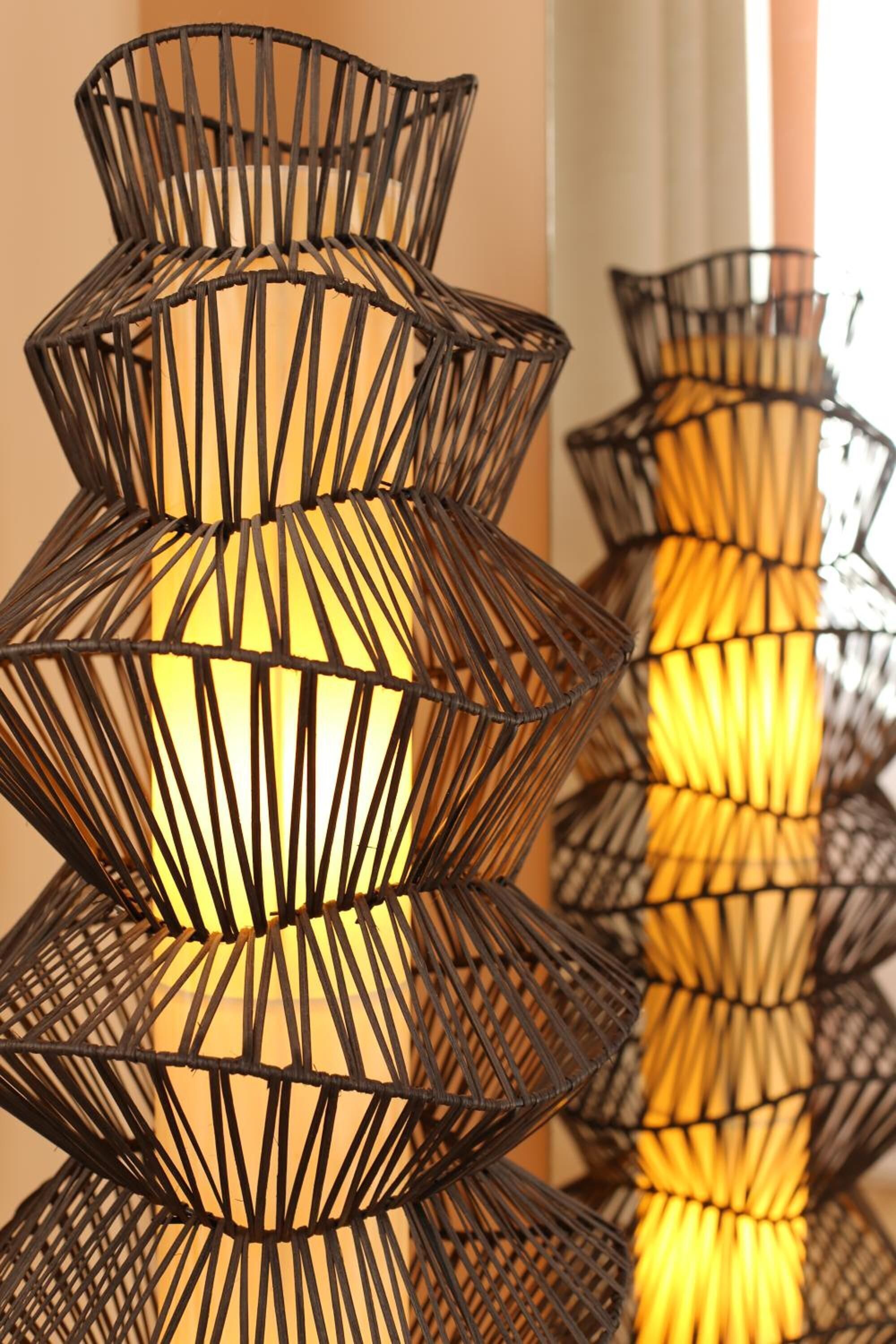 A series of geometric, black metal wall sconces with warm lighting.
