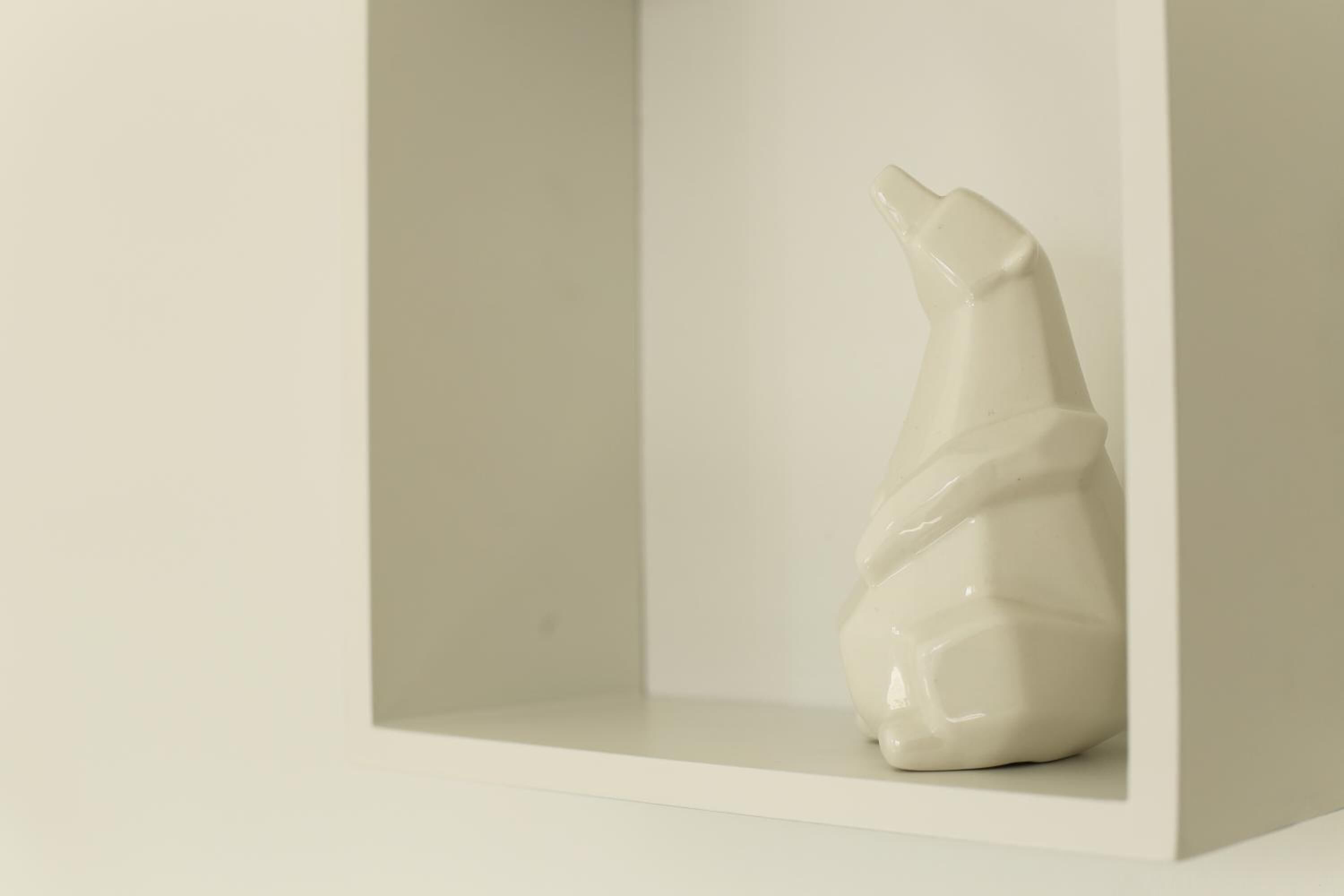 A white ceramic sculpture in a white display case.