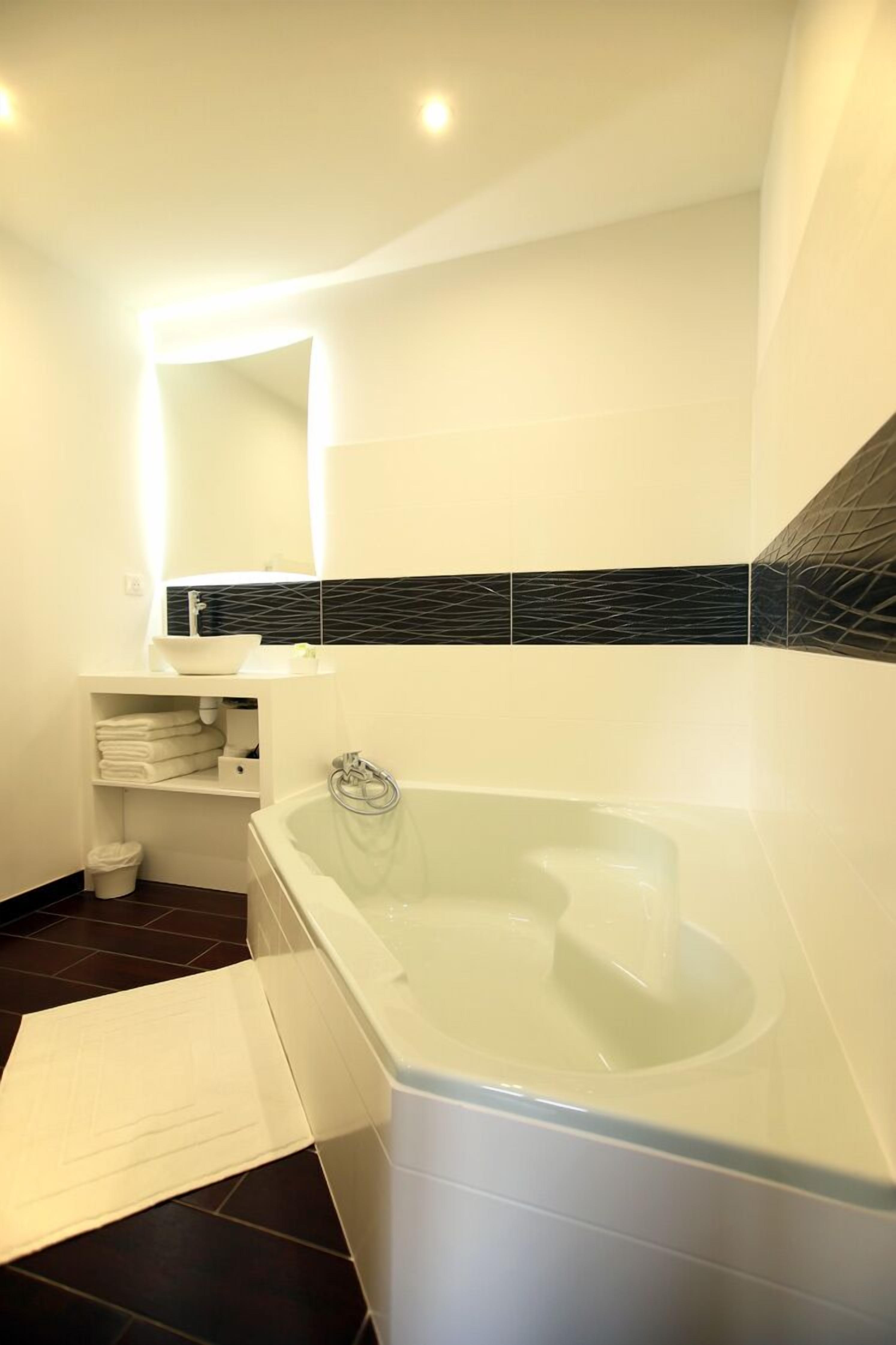 Ein modernes Badezimmer mit einer freistehenden Badewanne, einem weißen Waschtisch mit Spiegel und einer schwarz-weißen Fliesenspiegel.