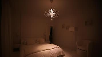 A dimly lit bedroom with a bed, a chair, and a hanging light fixture.