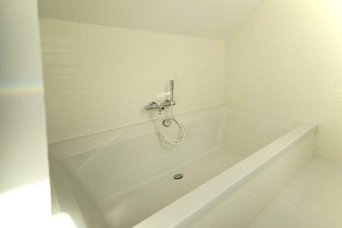 Une baignoire blanche avec un pommeau de douche et un drain.