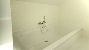 Une baignoire blanche avec un pommeau de douche et un drain.