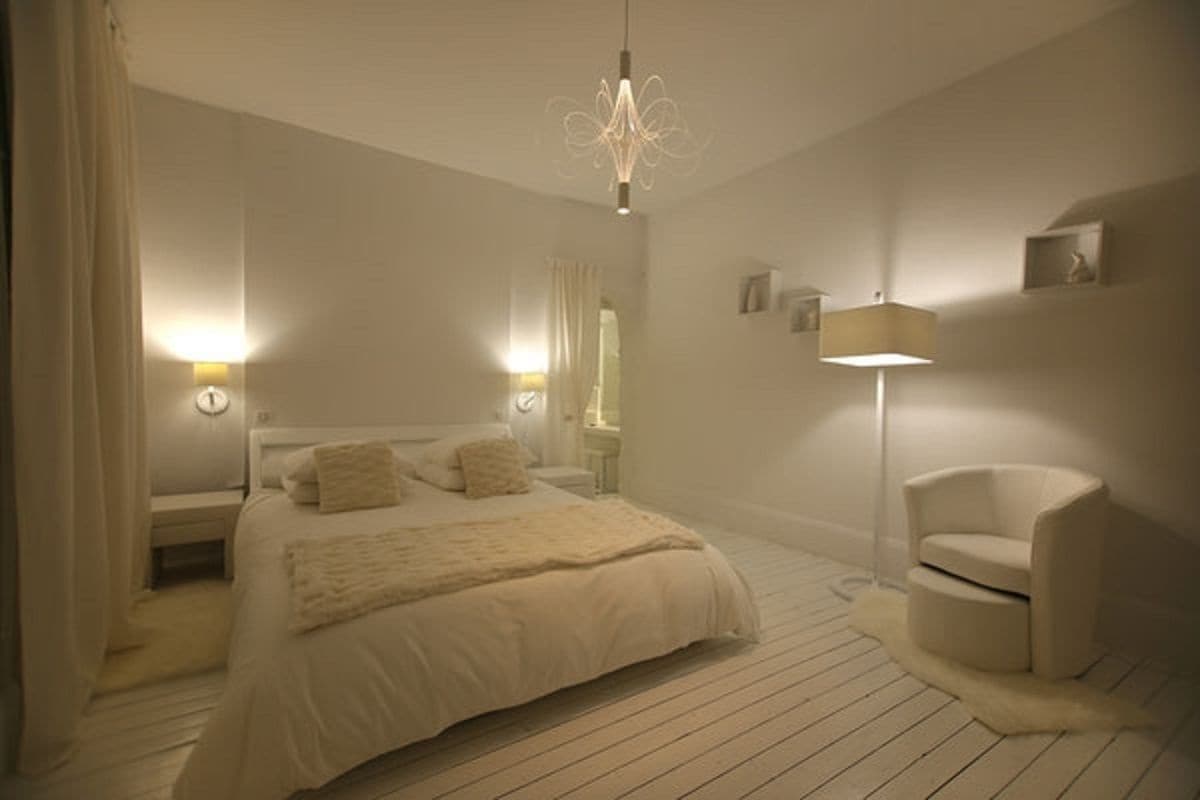 Une chambre à coucher avec un grand lit, des lampes de chevet, une chaise et une lampe sur pied.