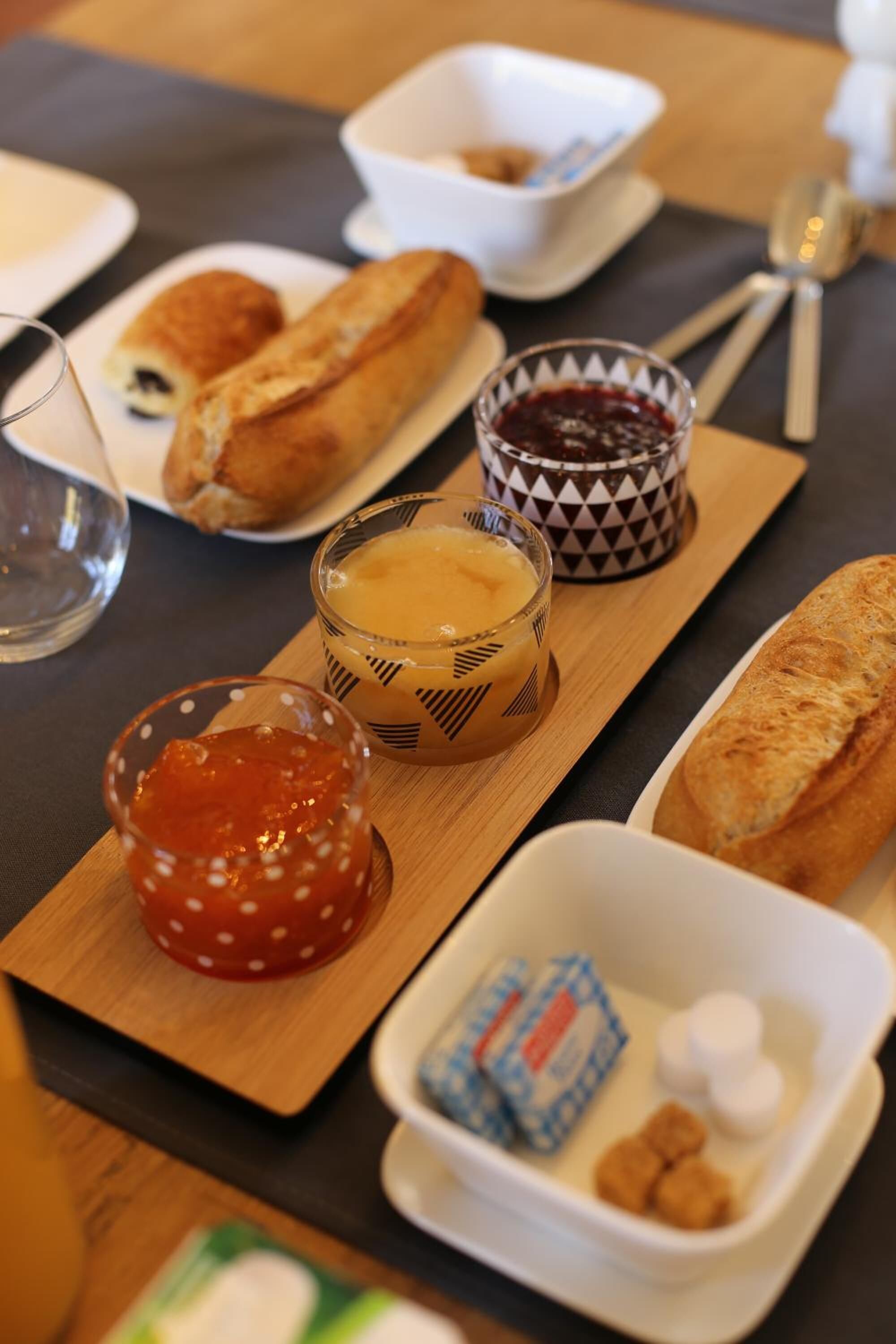 A table with various food items including croissants, jams, and butter.