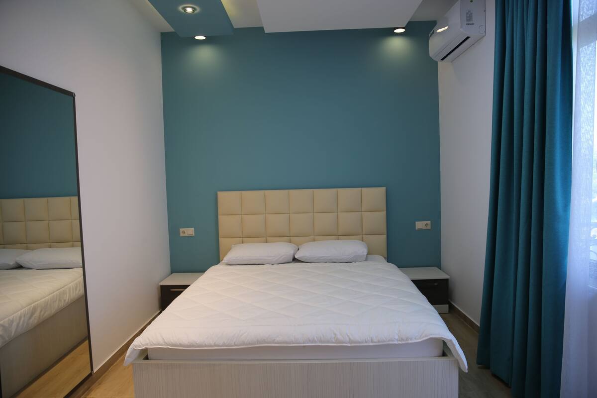 A bedroom with a bed, nightstands, and a window with curtains.
