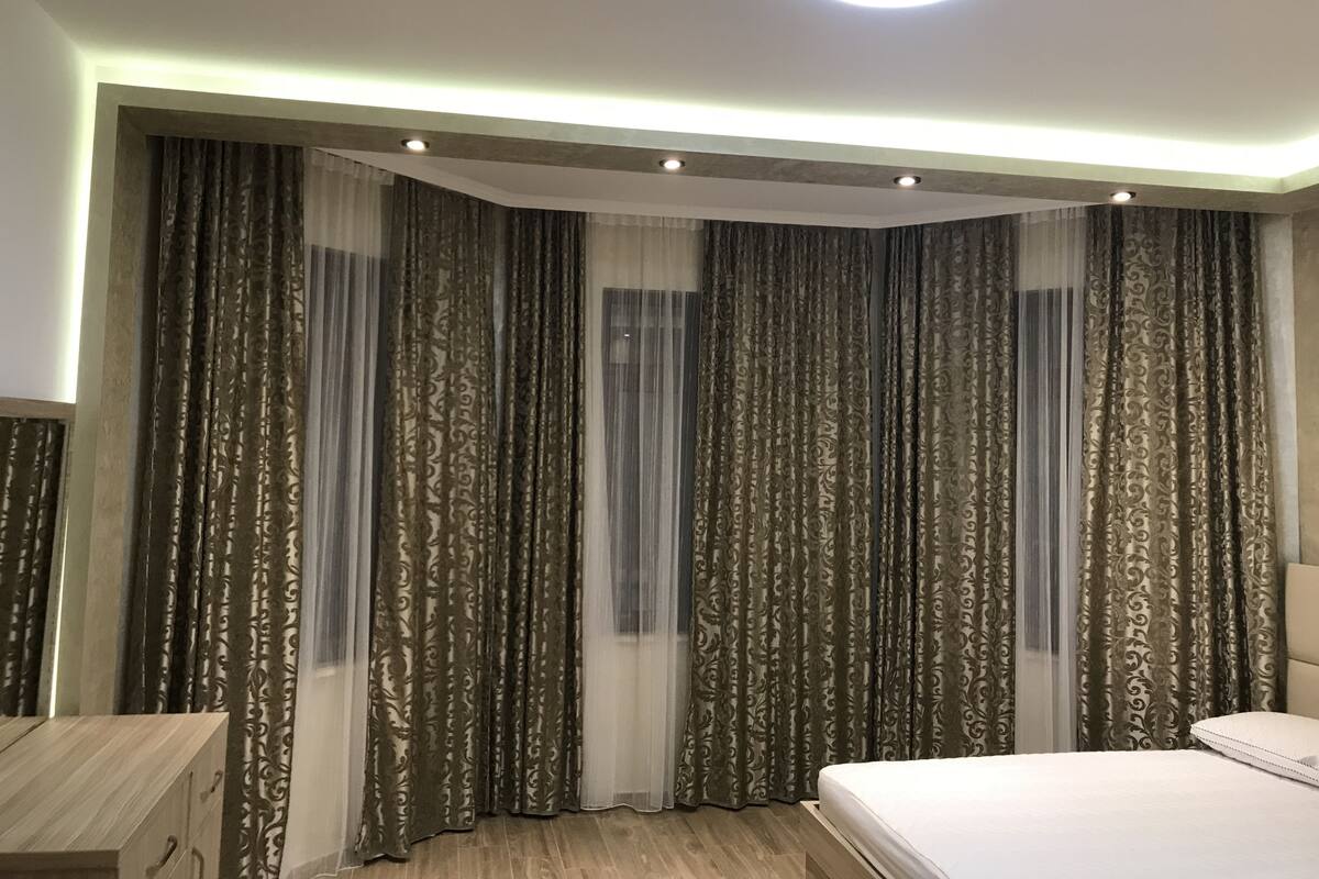 A modern bedroom with a large bed, a wooden nightstand, and a built-in wardrobe.