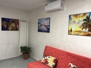 Una habitación con un sofá rojo, una planta en maceta y tres cuadros en la pared.