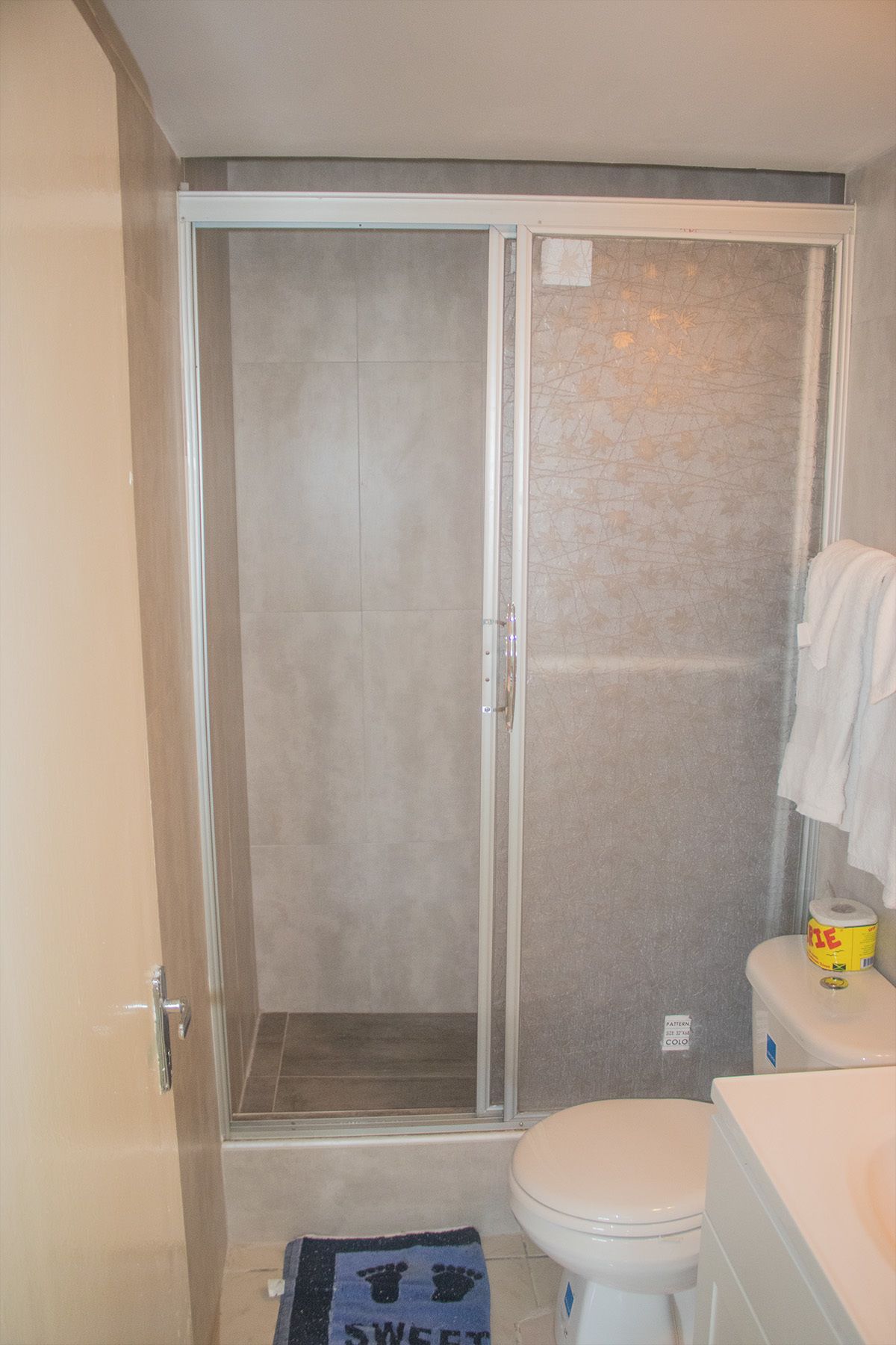 A bathroom with a shower enclosure, toilet, and a towel rack.
