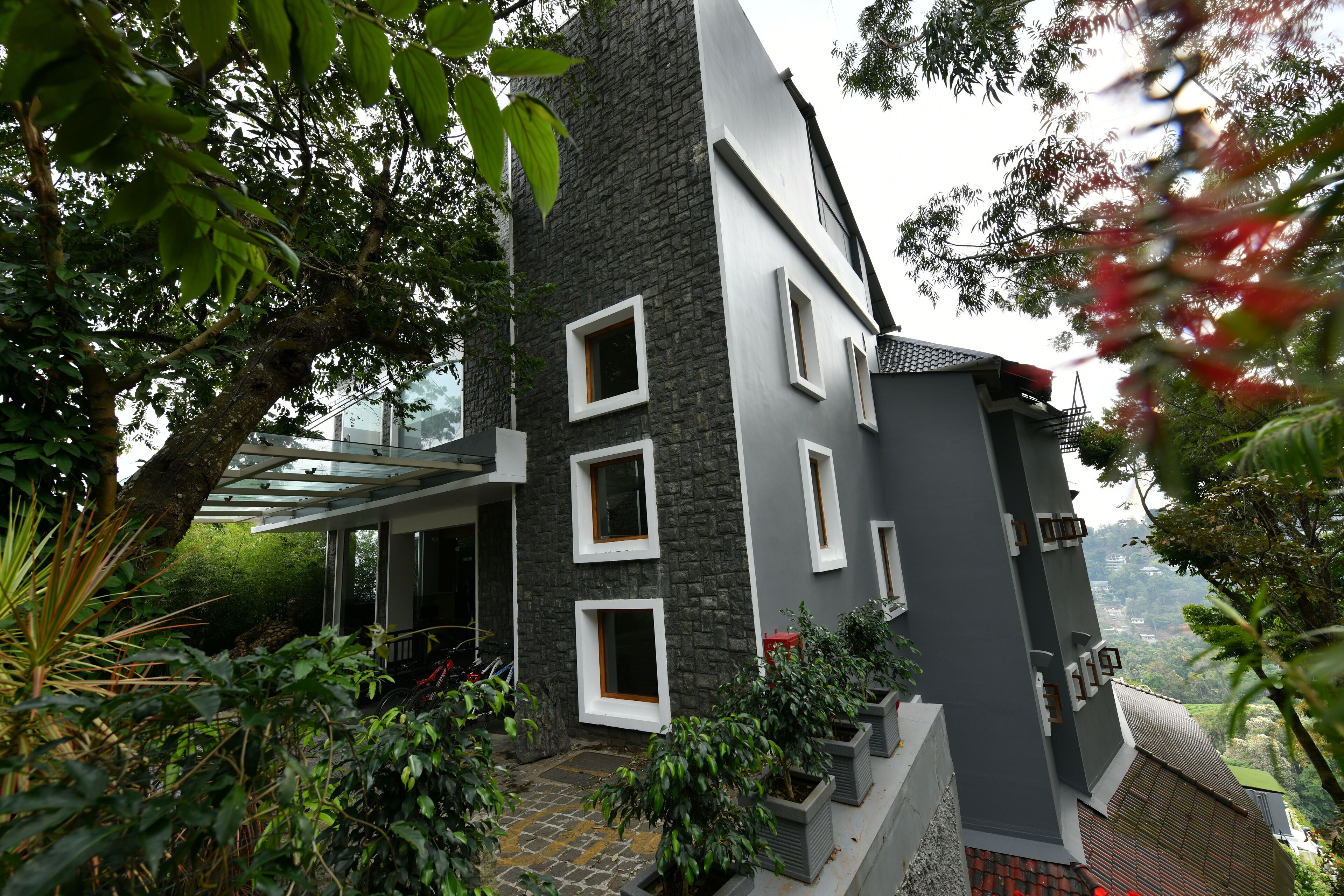 Un edificio moderno con fachada de piedra, múltiples ventanas y un acceso cubierto.